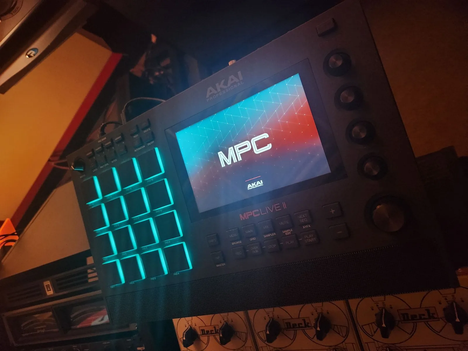 Photo of an Akai MPC Live II standalone sampler and beat machine, showing its touchscreen display, velocity-sensitive pad grid, and transport controls.