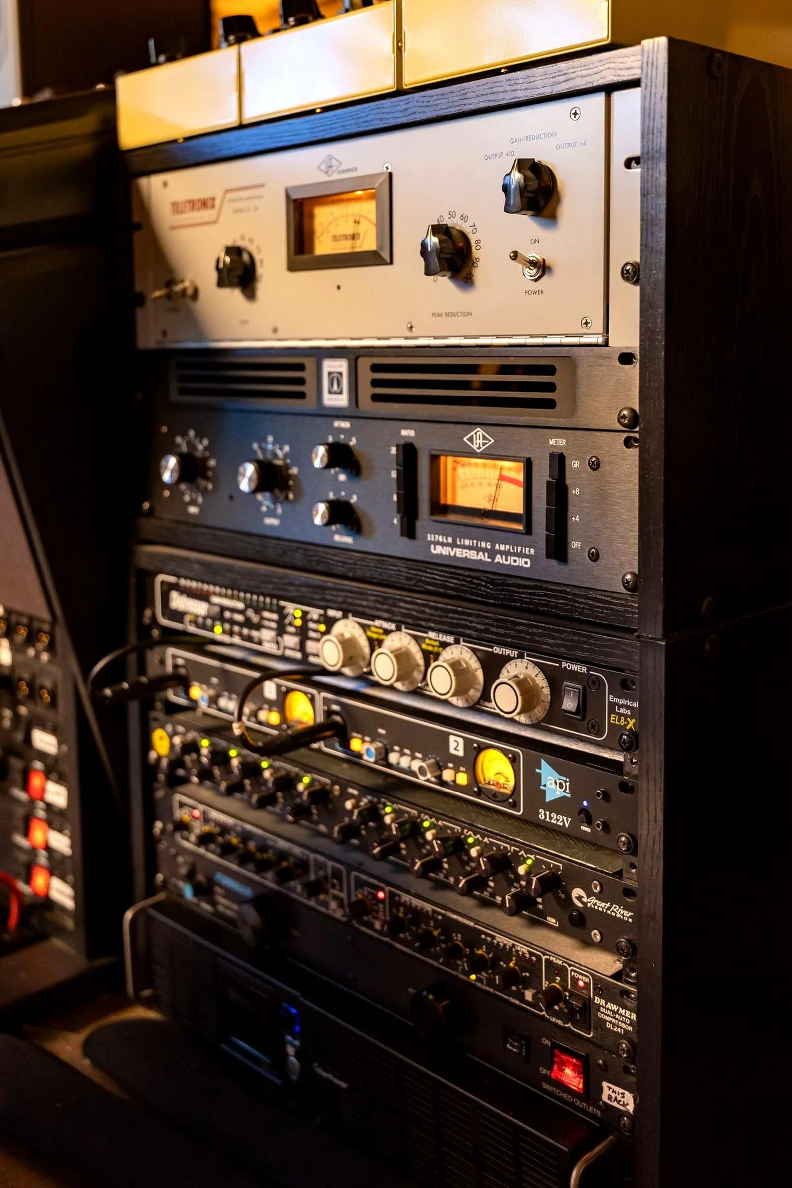 Photo of a 19-inch equipment rack containing a Teletronix LA-2A compressor, Universal Audio 1176LN, Empirical Labs Distressor, and API 3122V preamp mounted in rack-unit slots.