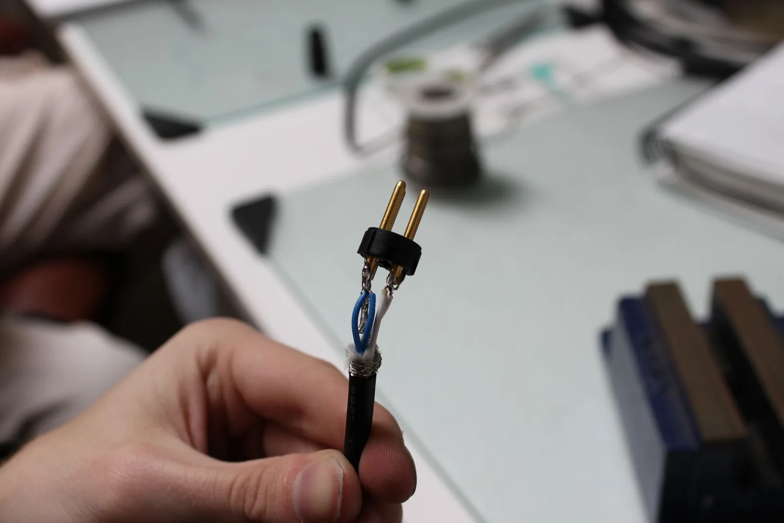 Close-up photo of a completed XLR insert showing the hot, cold, and shield wires soldered to the three gold-plated pin terminals.
